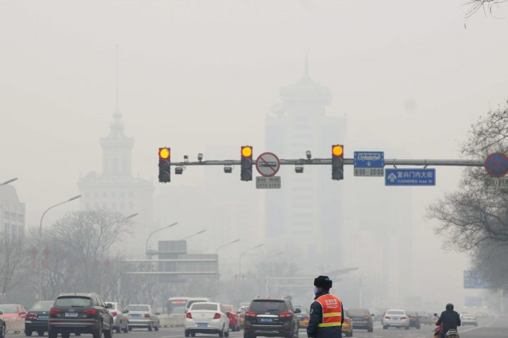 epa04098577 A picture made available 24 February 2014 shows a traffic worker looking at the traffic as smog covers Beijing, China, 23 February 2014. Due to smog alerts, a city in northern China has banned a fifth of residents' vehicles from roads, reports stated since 23 February. In Beijing, an orange alert had been issued on 21 February due to smog which is the second-highest of four levels of urgency. The Environmental Protection Ministry has sent 12 inspection teams to Beijing, Tianjin, Hebei and surrounding areas to check on compliance to measures to reduce air pollution. EPA/JASON FAN CHINA OUT